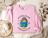 A pink sweatshirt with a graphic design depicting a fire-breathing trash can, accompanied by the text "It's fine, I'm fine Everything's fine".