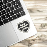 A laptop with a heart-shaped sticker on the palm rest, placed on a wooden surface.
