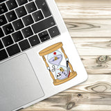a sticker with an illustration of a sand timer on a laptop keyboard.